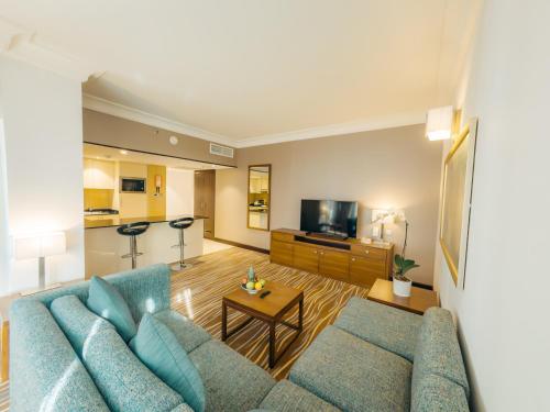 a living room with a blue couch and a tv at Copthorne Downtown by Millennium in Abu Dhabi
