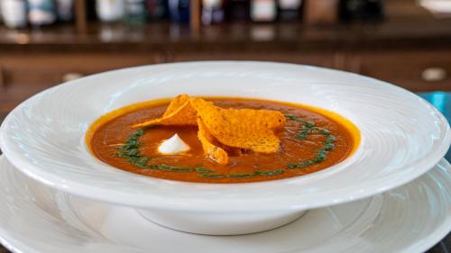 a bowl of soup with tortilla chips on a plate at Boutique Odyseja & Spa in Ciechocinek