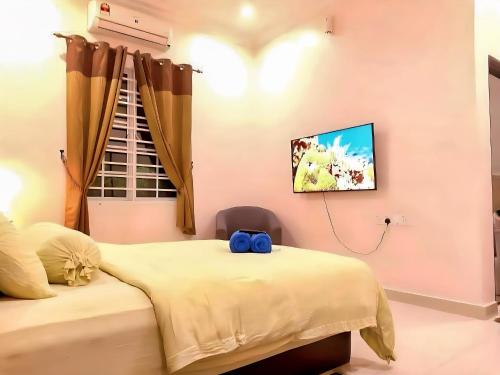 a bedroom with two beds and a tv on the wall at Homestay VillaSolihin Sungai Buloh in Sungai Buluh
