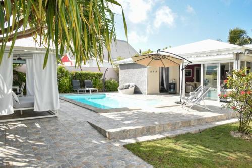a house with a swimming pool and an umbrella at Villa confortable à Sainte-Anne avec piscine privée in Sainte-Anne