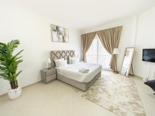 拉斯阿尔卡麦Hala Holiday Homes- Bab Al Bahr Residence, Al Marjan Island的白色卧室配有大床和植物