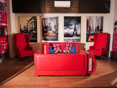 a red couch in a store with two red chairs at Meotel Purwokerto in Purwokerto