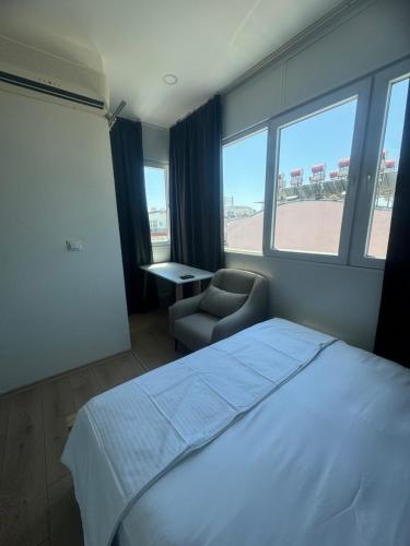 een slaapkamer met een bed, een stoel en ramen bij Turap Homes in Antalya