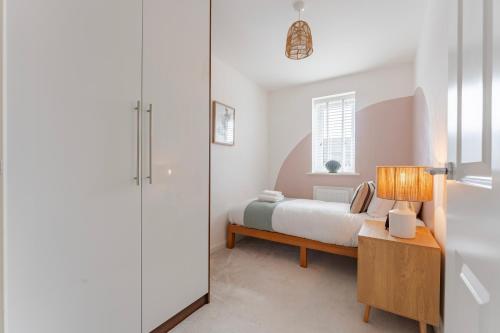 a bedroom with a bed and a table with a lamp at Stylish & Chic 3 bed House in Cambourne