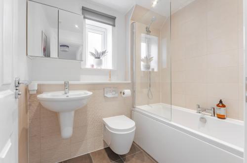 a bathroom with a sink and a toilet and a bath tub at Stylish & Chic 3 bed House in Cambourne