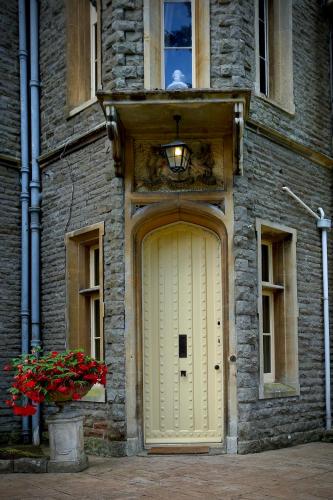 a yellow door on a stone building with a window at Llangattock Park House in Crickhowell