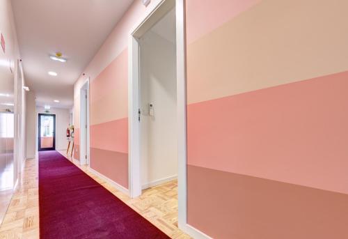 a hallway with pink and white walls and a purple carpet at Hotel do Mercado in Aveiro