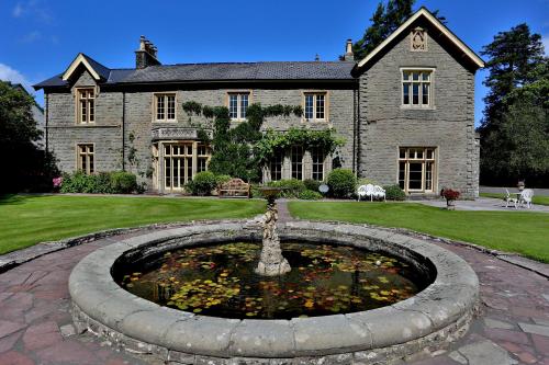 a large stone house with a pond in front of it at Llangattock Park House in Crickhowell