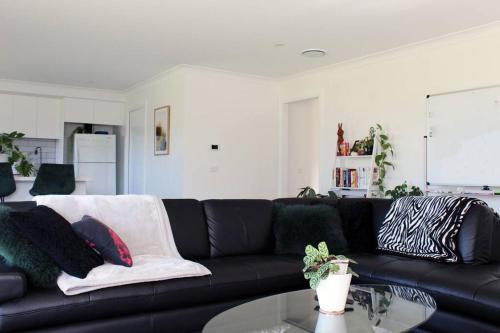 a living room with a black couch and a table at Brand New Luxury Build with Home Theatre in Kelso