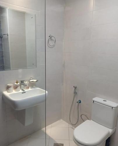 a bathroom with a toilet and a sink and a shower at Cozy Peaceful Single Room with Balcony and Attached Washroom in Al Ḩamīdīyah