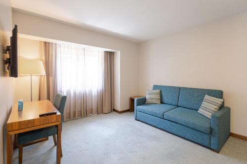 uma sala de estar com um sofá azul e uma secretária em Hotel Navarras em Amarante