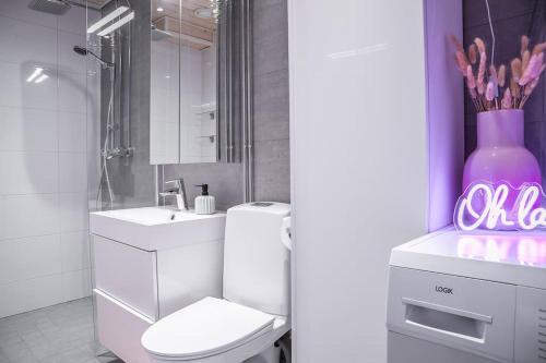 Un baño con inodoro, lavabo y un jarrón rosa. en Polar Night Shelter, en Rovaniemi