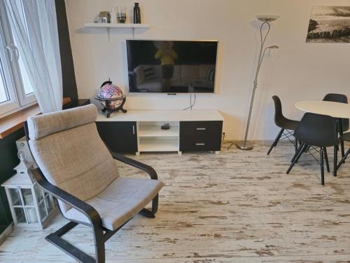 a living room with a chair and a tv and a table at Parkowy - Sweet House in Świnoujście