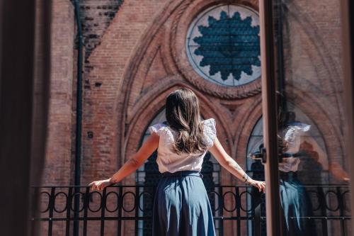 a woman standing on a balcony looking at a building at Art Hotel Commercianti in Bologna