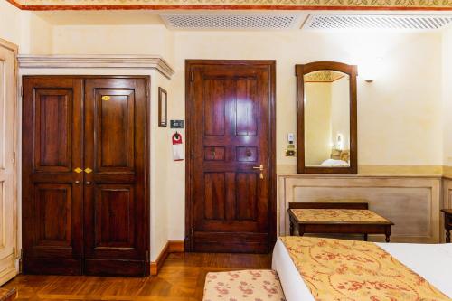a bedroom with a wooden door and a mirror at Art Hotel Commercianti in Bologna