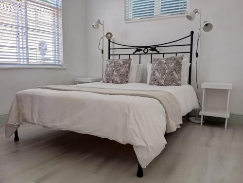 a bedroom with a large bed with white sheets and pillows at Boulders Beach Hotel, Cafe and Curio shop in Simonʼs Town