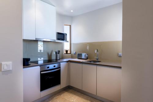 a kitchen with white cabinets and a black appliance at Camões Appartments in Porto