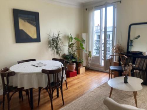 un salon avec une table et des chaises et une fenêtre dans l'établissement Appart 54m2 quartier Jourdain 75020 etage 5 sans ascenseur, à Paris