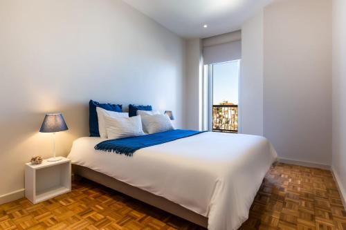 a bedroom with a large white bed and a window at Camões Appartments in Porto