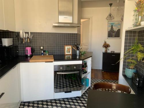 - une cuisine équipée d'un four avec plaques de cuisson en noir et blanc dans l'établissement Appart 54m2 quartier Jourdain 75020 etage 5 sans ascenseur, à Paris