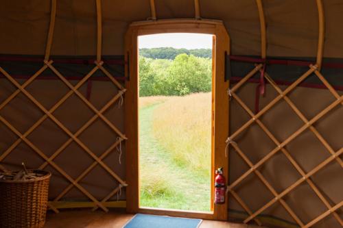 a door in a tent with a view of a field at Ash Yurt in Kent