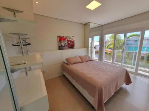 a bedroom with a bed and a large window at Casa de Verão no Malibu à Beira do Lago in Xangri-lá