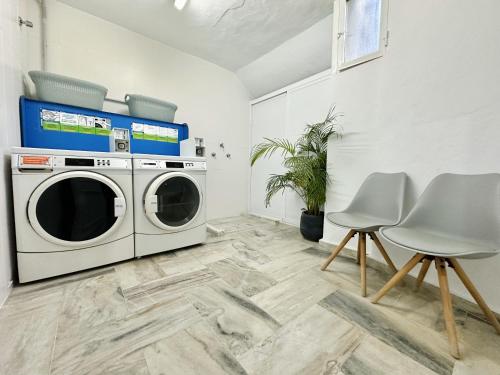 a laundry room with a washing machine and two chairs at Hotel Apartamentos Marina Luz in Chipiona