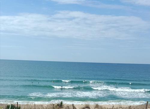 a group of surfers riding the waves in the ocean at L'Océan&Dunes vue à 180° en bord de plage in Lacanau-Océan