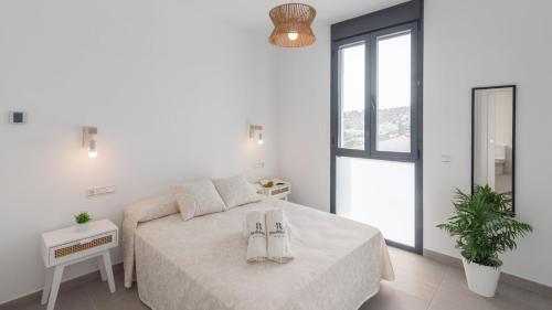 a white bedroom with a bed and a window at Rva de las Nieves - Pecho de Venus by Ruralidays in Tolox