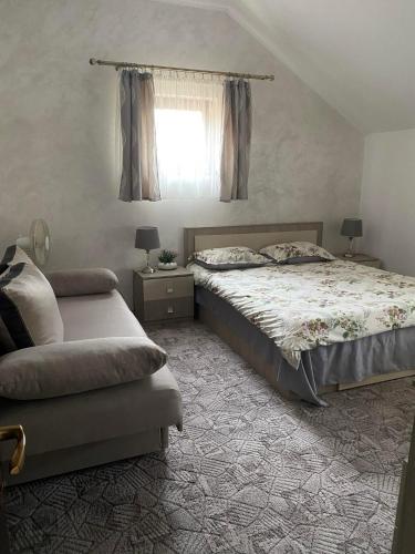 a bedroom with a bed and a couch and a window at Pensiunea Floris in Vaţa de Jos