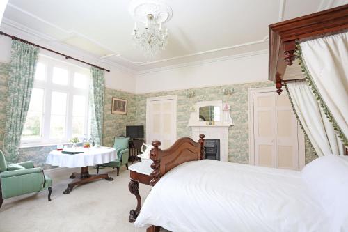 a bedroom with a bed and a table and a chandelier at Llangattock Park House in Crickhowell
