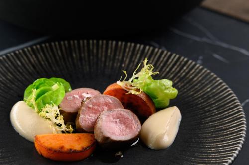 a plate of food with meat and vegetables on a table at Melea - The Health Concept - Adults Only Hotel in Sárvár