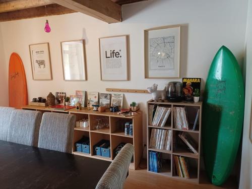 a living room with a surfboard and a book shelf at Les chambres du Nid charentais in La Poterie