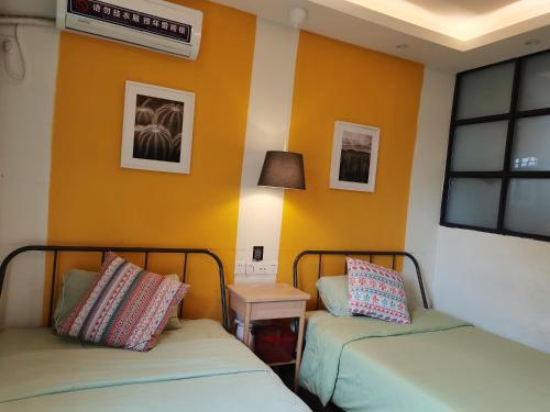 two beds in a room with orange walls at XiXi Lakeside Inn in Guilin