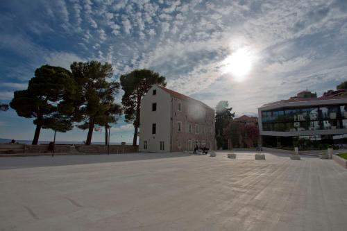 a building in a square with a cloudy sky at Maistra Select Mlini Hotel in Mlini
