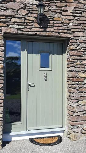 a green door in a stone building with a window at B&B Kerry Lakesview Lodge in Waterville