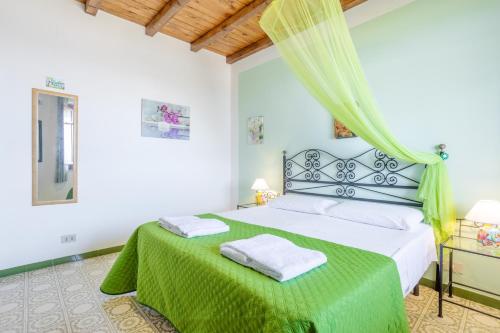 a bedroom with a bed with a green bedspread at Villa Le 2 Palme in Isola delle Femmine