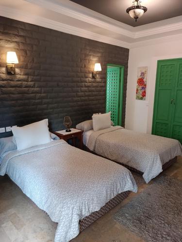two beds in a room with two green doors at Dar Riad Niama in Taroudant