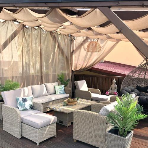a patio with white wicker furniture and a canopy at Penzion Sokolská in Zlín