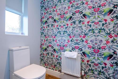 a bathroom with a toilet and a floral shower curtain at Spacious Comfort for Contractors & Long-Term Guests in Saighton