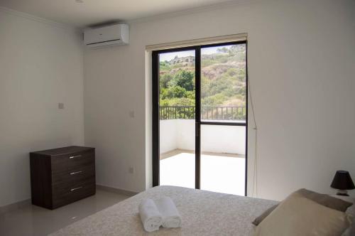 Un dormitorio con una cama y vista a un balcón. en Penthouse Ghadira With Amazing Views! By Homely, en Mellieħa