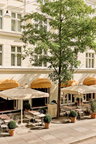 a patio with tables and umbrellas in front of a building at Hotel Bella Grande in Copenhagen