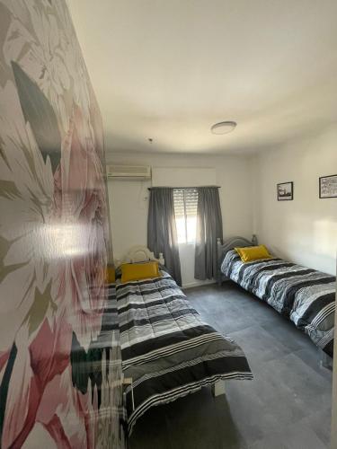 Una habitación con dos camas y un cuadro en la pared. en Cómo en casa, en Resistencia