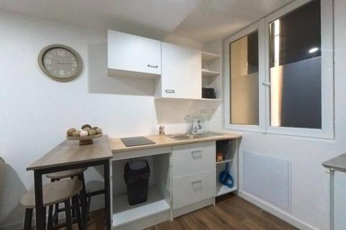 une petite cuisine avec un évier et une horloge murale dans l'établissement Charmant Studio au cœur du centre historique, à Béziers