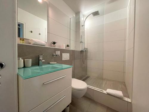 une salle de bain avec un lavabo, des toilettes et une douche dans l'établissement PGH N37 - Vue Mer et Port, 8eme étage, Parking Privé, à La Grande Motte