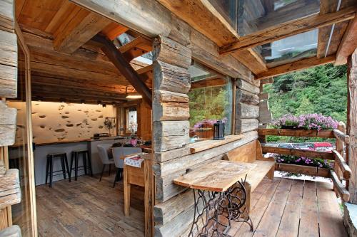 a large wooden porch with a wooden table in a cabin at Lo Pailler de Mamma e Pappa in Valsavarenche