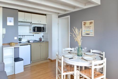 une cuisine et une salle à manger avec une table et des chaises blanches dans l'établissement L’Oasis des Nouveaux Bassins - apt vue port, à Courseulles-sur-Mer