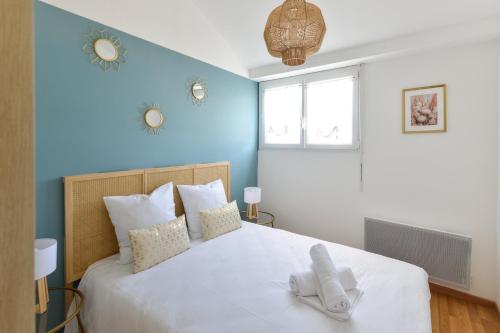 une chambre avec un grand lit blanc avec des murs bleus dans l'établissement L’Oasis des Nouveaux Bassins - apt vue port, à Courseulles-sur-Mer