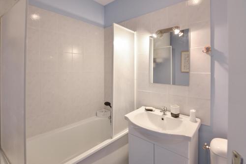une salle de bain blanche avec un lavabo et une douche dans l'établissement L’Oasis des Nouveaux Bassins - apt vue port, à Courseulles-sur-Mer