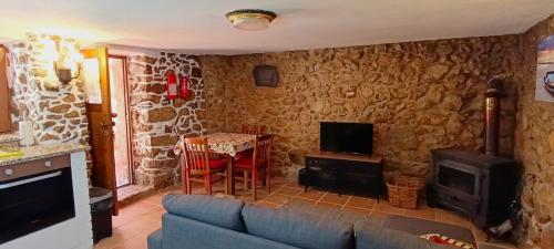 a living room with a couch and a tv and a table at Casas do Favacal in Penela